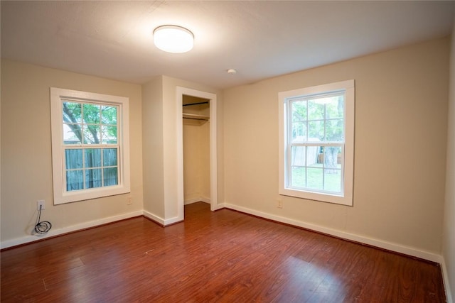 unfurnished bedroom with baseboards, dark wood-style flooring, and multiple windows