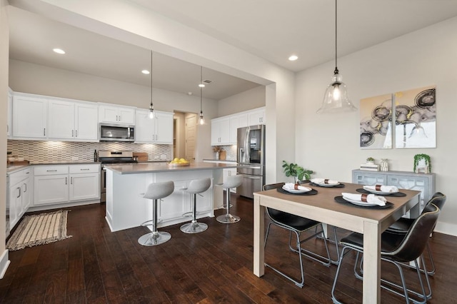 6800 Idea Rd, Austin, TX 78741 - kitchen featuring a center island, a kitchen bar, decorative backsplash, dark wood-type flooring, and appliances with stainless steel finishes