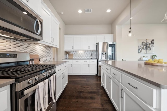6800 Idea Rd, Austin, TX 78741 - kitchen with dark wood-style flooring, visible vents, backsplash, white cabinets, and appliances with stainless steel finishes