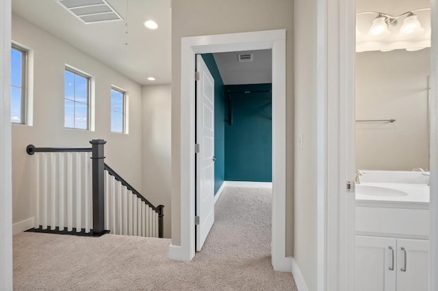 6800 Idea Rd, Austin, TX 78741 - hallway featuring carpet flooring, an upstairs landing, a sink, visible vents, and baseboards