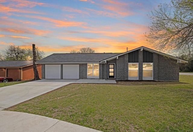 view of front of property featuring a yard, a garage, and driveway