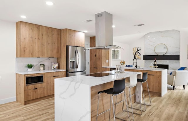 2927 Norwood Hill Rd, Austin, TX 78723 - kitchen featuring appliances with stainless steel finishes, modern cabinets, island range hood, light wood finished floors, and recessed lighting
