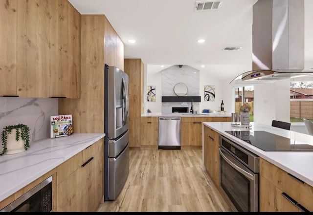 kitchen featuring modern cabinets, stainless steel appliances, visible vents, and wall chimney exhaust hood