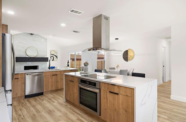 kitchen featuring modern cabinets, light wood finished floors, visible vents, island range hood, and stainless steel appliances