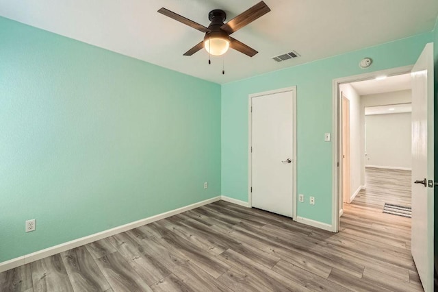 unfurnished bedroom with baseboards, visible vents, a ceiling fan, and wood finished floors