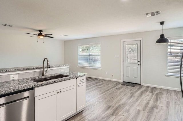 305 Bird Dog Bnd, Bastrop, TX 78602 - kitchen featuring dishwasher, a sink, stone countertops, white cabinets, and light wood-style floors