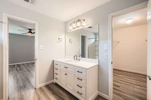 305 Bird Dog Bnd, Bastrop, TX 78602 - bathroom featuring vanity, wood finished floors, a walk in closet, a ceiling fan, and baseboards
