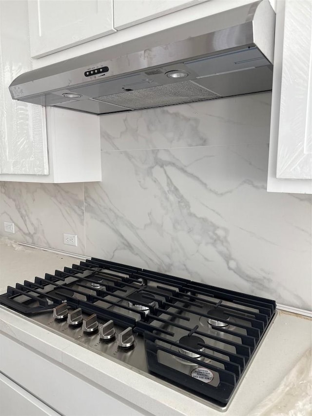 1033 Blanket Flower Dr, Georgetown, TX 78628 - interior details with decorative backsplash, stainless steel gas stovetop, under cabinet range hood, and white cabinets