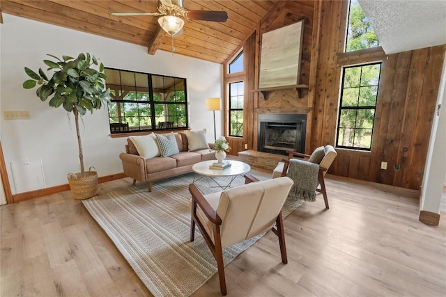 living area with a fireplace with raised hearth, light wood-style flooring, baseboards, and ceiling fan