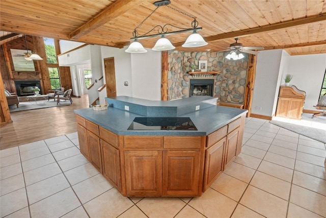 kitchen featuring wooden ceiling, ceiling fan, open floor plan, and a stone fireplace