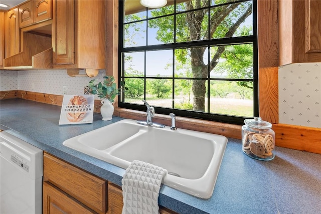 kitchen featuring a sink, dark countertops, white dishwasher, and brown cabinets