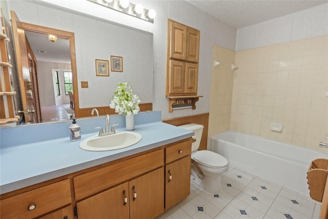 full bath with a textured ceiling, toilet, tile patterned floors, vanity, and bathing tub / shower combination