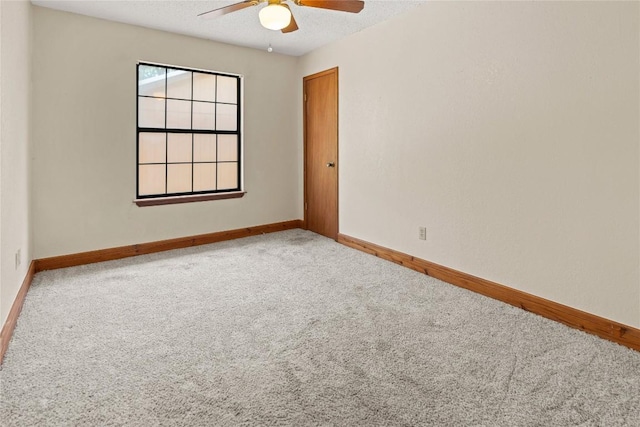carpeted spare room featuring a textured ceiling, baseboards, and a ceiling fan