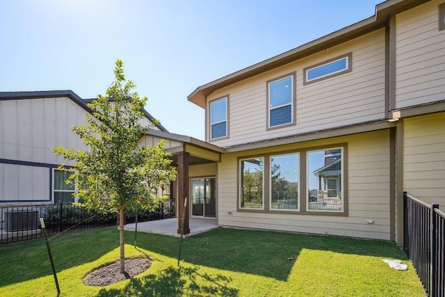 rear view of property featuring a yard, a fenced backyard, and a patio