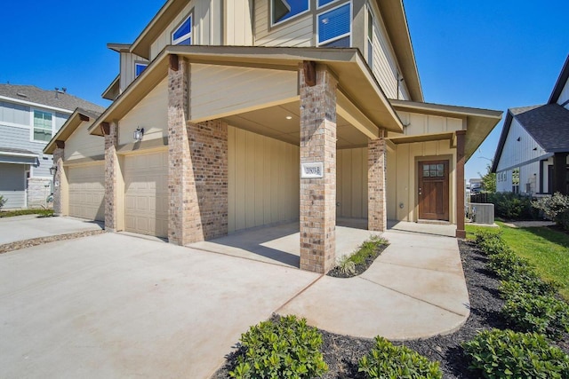 view of front of house featuring an attached garage, board and batten siding, central AC unit, brick siding, and driveway