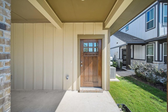 doorway to property featuring board and batten siding and central AC unit