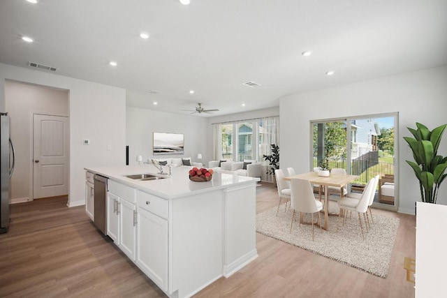 kitchen featuring a sink, stainless steel appliances, white cabinetry, visible vents, and light wood-style floors