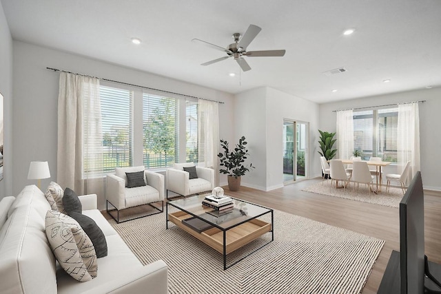 living area with plenty of natural light, visible vents, wood finished floors, and a ceiling fan