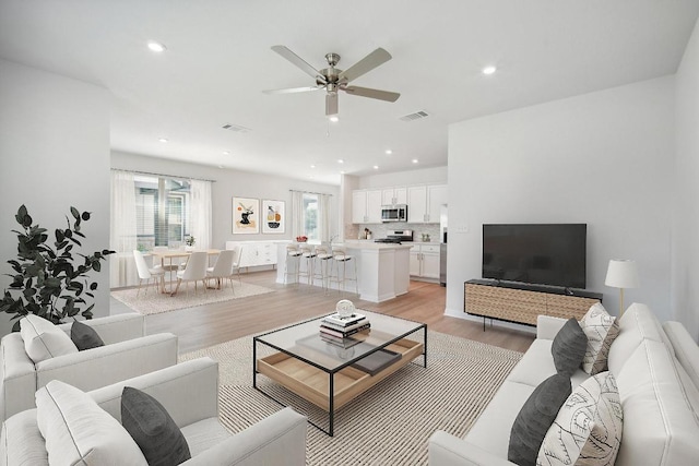 living room featuring a ceiling fan, recessed lighting, light wood-style floors, and visible vents