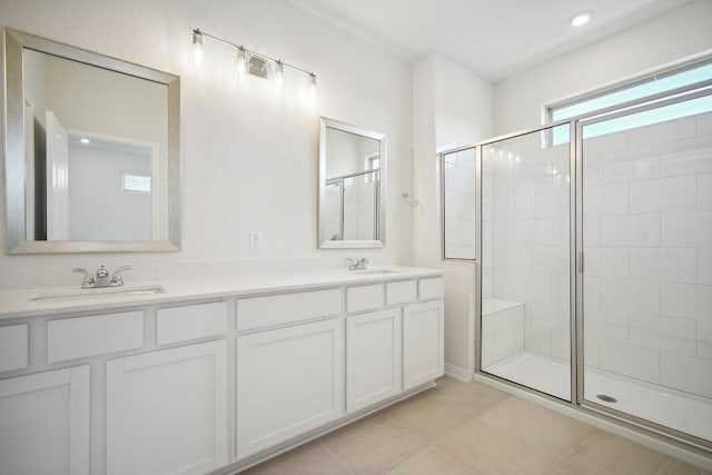 full bathroom with tile patterned floors, double vanity, a stall shower, and a sink