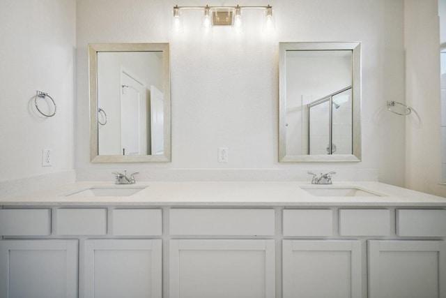 full bathroom featuring double vanity, a stall shower, and a sink