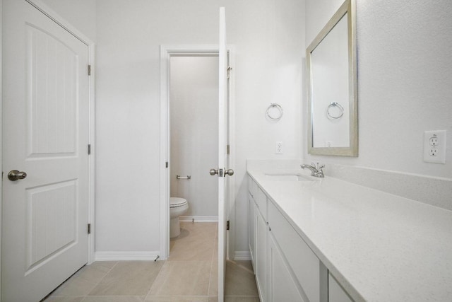 bathroom with toilet, baseboards, tile patterned floors, and vanity