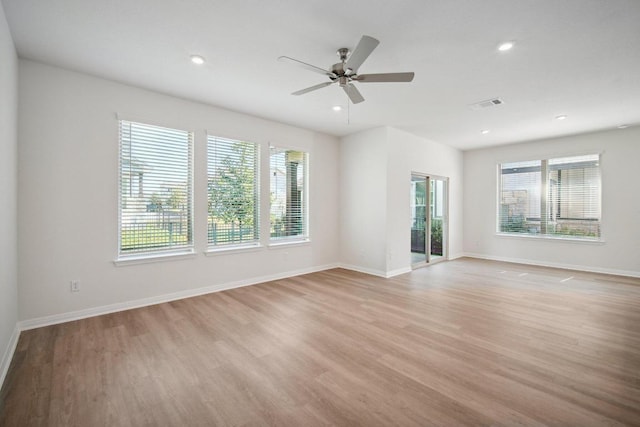 empty room with light wood finished floors, a wealth of natural light, and visible vents