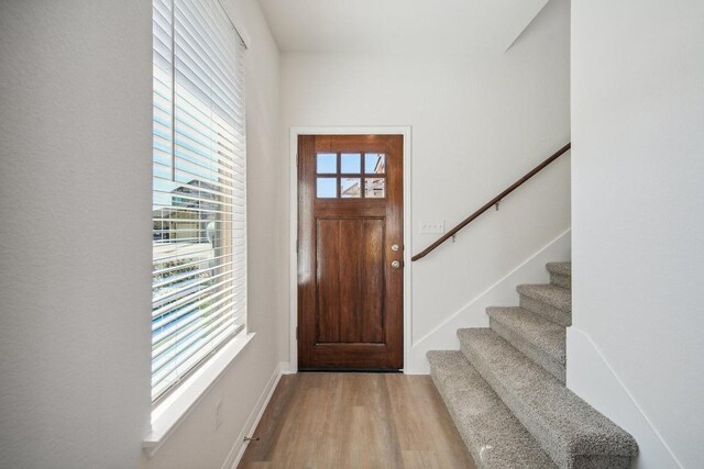 foyer with baseboards, stairs, and wood finished floors