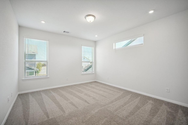 carpeted empty room with plenty of natural light, visible vents, and baseboards