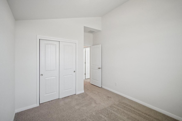 unfurnished bedroom featuring a closet, carpet, baseboards, visible vents, and vaulted ceiling