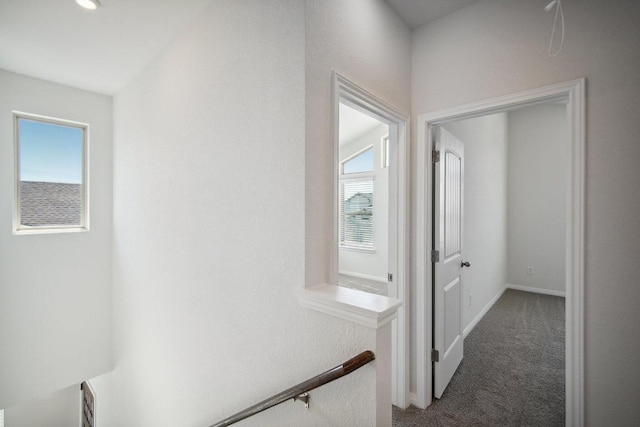 hall with baseboards, carpet flooring, and an upstairs landing