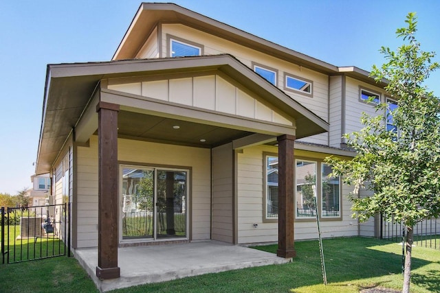 back of house featuring a lawn, board and batten siding, a patio, and fence