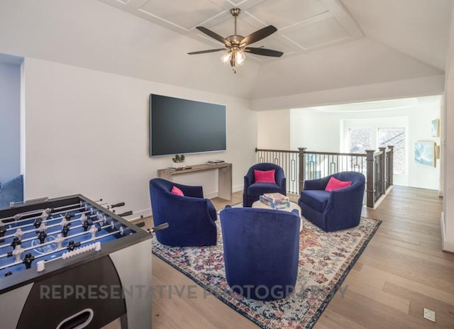 living area with baseboards, wood finished floors, ceiling fan, and vaulted ceiling
