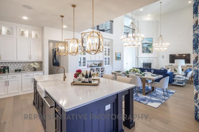 kitchen with an inviting chandelier, a sink, open floor plan, light wood-type flooring, and stainless steel dishwasher