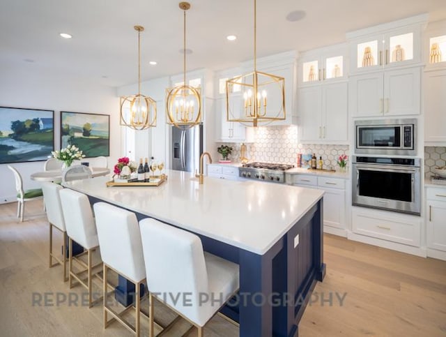 kitchen featuring an inviting chandelier, light wood-style floors, stainless steel appliances, and tasteful backsplash