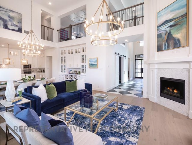 living area with baseboards, a chandelier, a towering ceiling, wood finished floors, and a fireplace