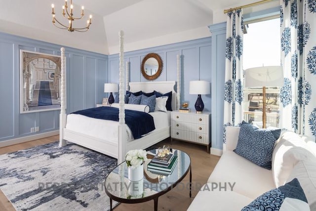 bedroom with multiple windows, a notable chandelier, a decorative wall, and wood finished floors