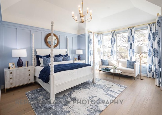 bedroom featuring a decorative wall, an inviting chandelier, and wood finished floors
