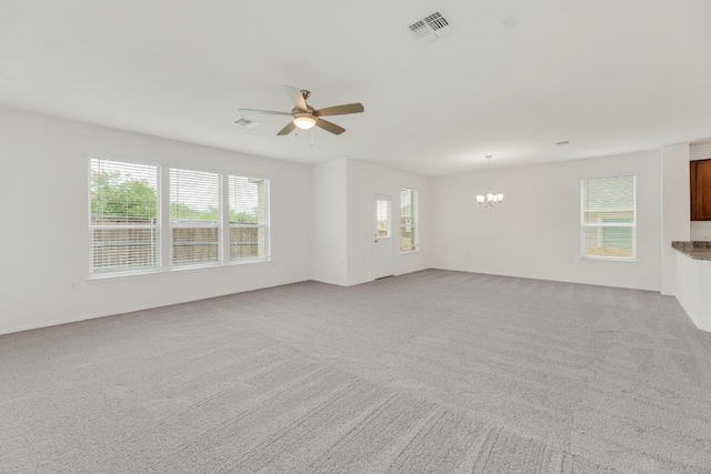 empty room with light carpet, ceiling fan with notable chandelier, and visible vents