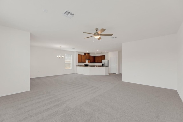 unfurnished living room with recessed lighting, light carpet, visible vents, and ceiling fan with notable chandelier