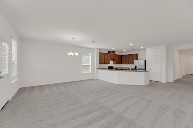 kitchen featuring light carpet, open floor plan, appliances with stainless steel finishes, and a chandelier
