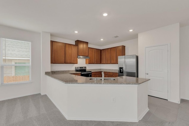 kitchen with a sink, under cabinet range hood, light stone counters, and appliances with stainless steel finishes