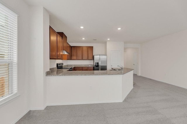 kitchen featuring brown cabinets, a sink, stainless steel appliances, light colored carpet, and recessed lighting