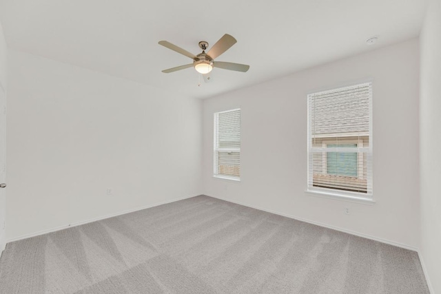 unfurnished room featuring a ceiling fan, light carpet, and baseboards