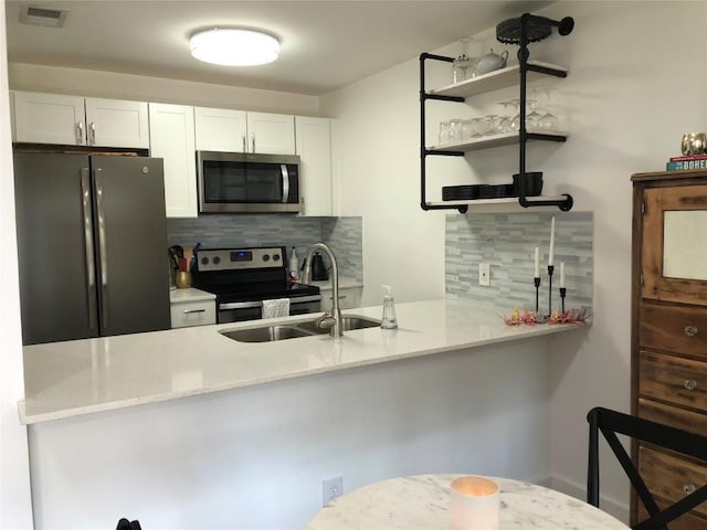 6409 Burns St Unit 306, Austin, TX 78752 - kitchen with visible vents, a sink, a peninsula, stainless steel appliances, and tasteful backsplash