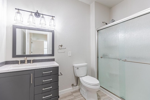 bathroom with vanity, toilet, baseboards, and a shower stall