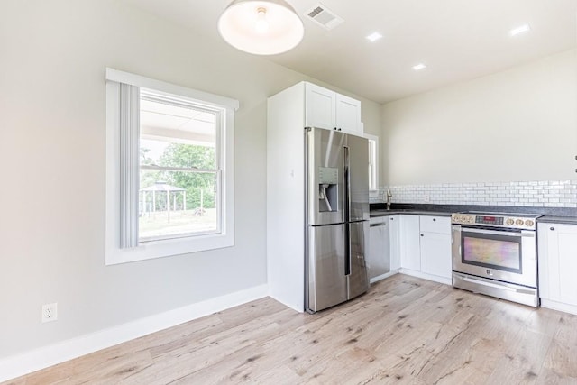 kitchen featuring a sink, stainless steel appliances, visible vents, white cabinetry, and decorative backsplash