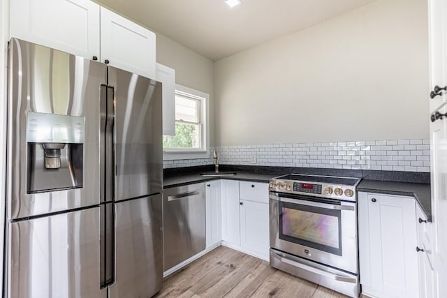 kitchen with white cabinetry, dark countertops, appliances with stainless steel finishes, and a sink