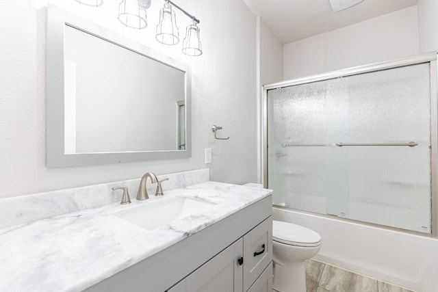 full bathroom with toilet, vanity, enclosed tub / shower combo, and wood finished floors