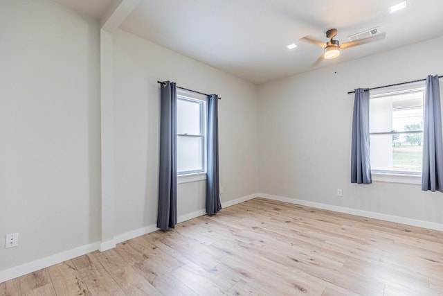 unfurnished room featuring light wood finished floors, plenty of natural light, and visible vents